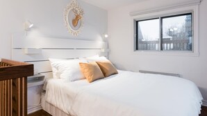 Ein Schlafzimmer mit Bett, Nachttischen, einer Wanddekoration und einem Fenster.