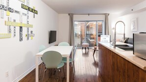 Eine moderne Küche mit Holzarbeitsplatte, einem Spülbecken und einem Essbereich mit weißem Tisch und grünen Stühlen.