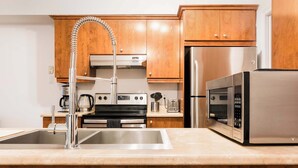 Eine moderne Küche mit Edelstahlgeräten, Holzschränken und einem eingebauten Backofen.