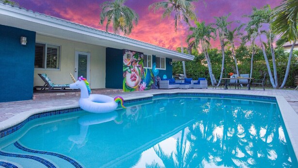 A swimming pool with a white swan float, lounge chairs, and a mural on the building.