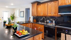A modern kitchen with wooden cabinets, a black countertop, and stainless steel appliances.