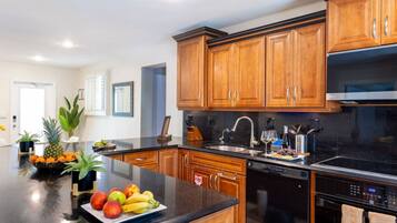 Una cocina moderna con armarios de madera, encimera negra y electrodomésticos de acero inoxidable.