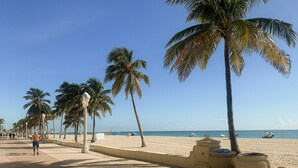 Una passeggiata sulla spiaggia con palme, un sentiero sabbioso e una vista libera sull'oceano.