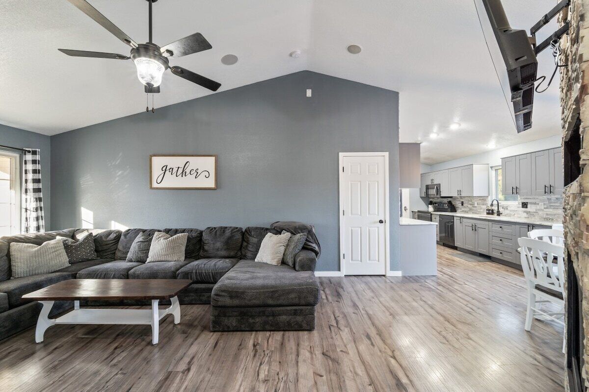 A modern living room with a sectional sofa, a coffee table, and a ceiling fan.