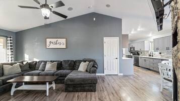 A modern living room with a sectional sofa, a coffee table, and a ceiling fan.