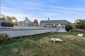 A backyard with a covered patio, a wooden bench, and a small table. - Huge Home, Gym, Game Room, Spa, BBQ, Near I-35 (Ankeny)