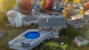A residential area with a swimming pool, a covered deck, and a house with a garage.