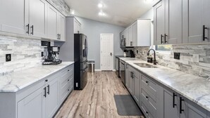 Une cuisine moderne avec des meubles gris, un plan de travail en marbre et un plancher en bois.