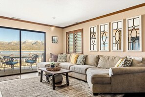 A living room with a large window, a sofa, a coffee table, and a view of mountains.