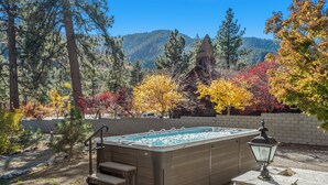 A hot tub with steps and a stone lamp post, surrounded by trees with autumn foliage and a mountain in the background. - Luxary Castle & SPA near Skiing Resort (Wrightwood)
