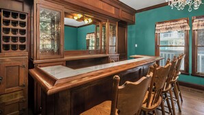 A wooden bar area with a marble countertop, wooden chairs, and a large mirror cabinet. - Luxary Castle & SPA near Skiing Resort (Wrightwood)
