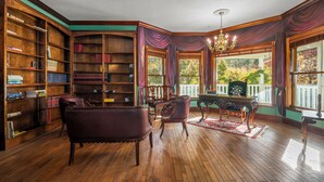 A library with wooden bookshelves, leather chairs, a billiards table, and large windows with a view of trees. - Luxary Castle & SPA near Skiing Resort (Wrightwood)