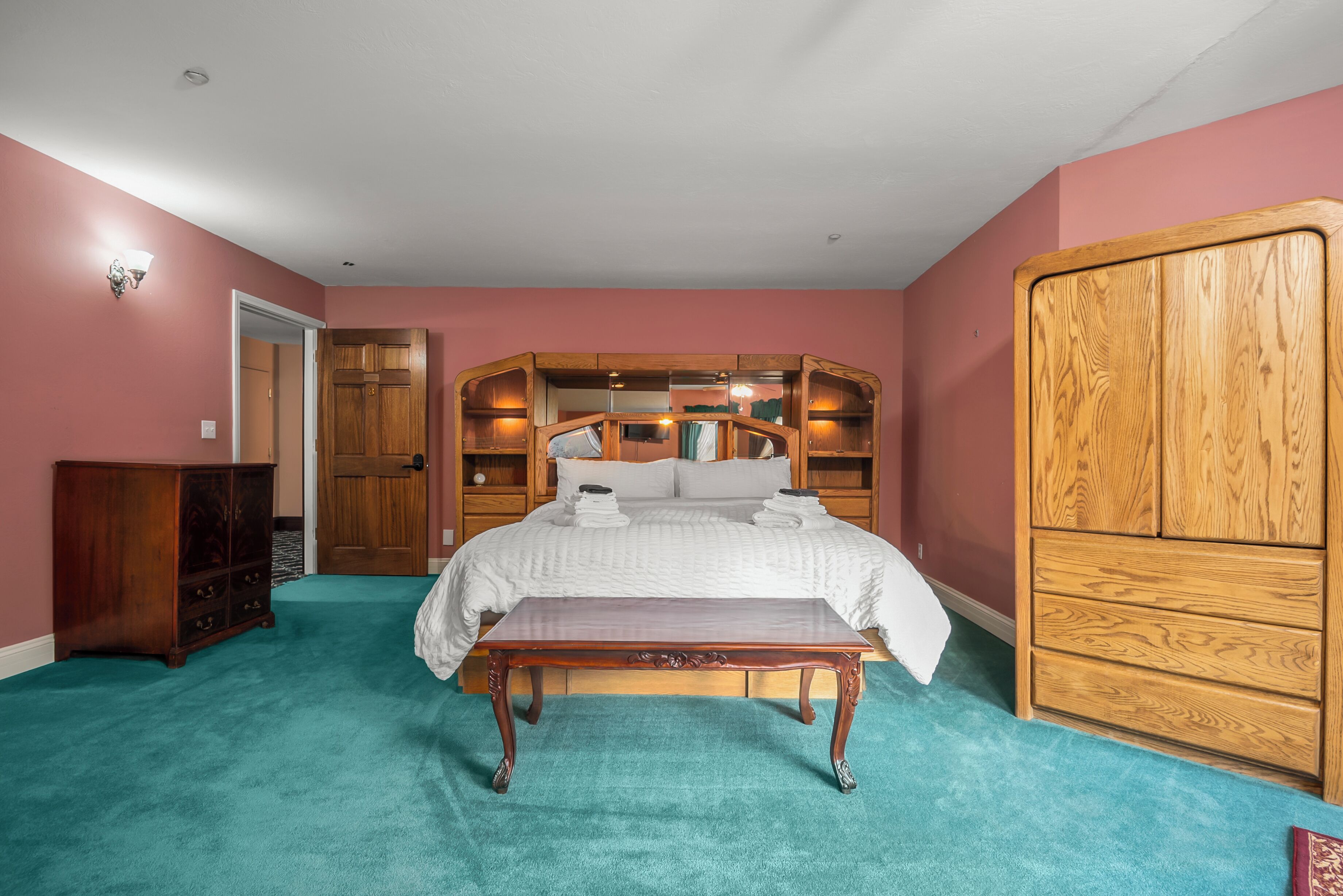 Un dormitorio con cama, armario de madera, mesita de noche y cómoda.