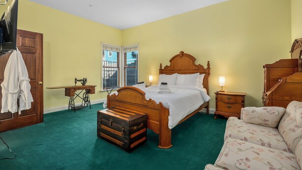 A bedroom with a wooden bed, a green carpet, a wooden desk, and a suitcase. - Luxary Castle & SPA near Skiing Resort (Wrightwood)