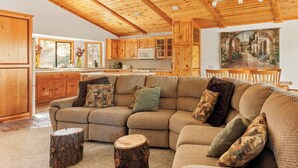 Ein gemütliches Wohnzimmer mit einer Eckcouch, Holzboden und Holzbalkendecke.