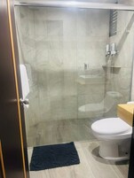 Un baño moderno con cabina de ducha de vidrio, un inodoro y un perchero para toallas.