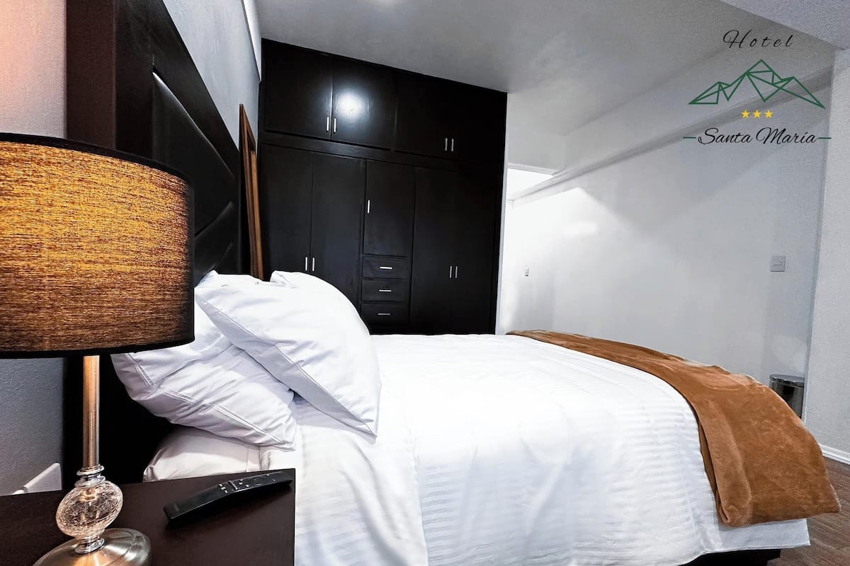 A hotel room with a bed, a lamp, and a wardrobe.