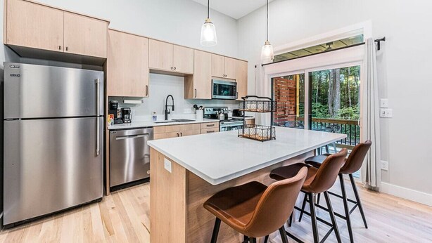 A modern kitchen with stainless steel appliances, wooden cabinets, and a large island with bar stools.
