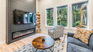 A modern living room with a fireplace, large windows, and a comfortable seating area.