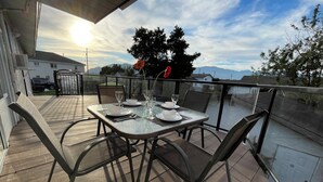 A deck with a table set for dining, overlooking a body of water and distant mountains. - Cozy , spacious and comfortable house. Pet friendly! And close to everything!!! (Chilliwack)