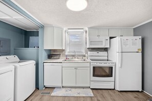 Una cocina compacta con electrodomésticos blancos, lavavajillas y microondas.