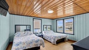 A room with two beds, wooden ceiling, large windows, and a view of the outside. - Blue Heron, Student/Pet Friendly w/ on Ocean Blvd (North Myrtle Beach)