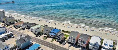 A coastal town with a beach, buildings, and a pier.
