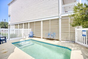 A swimming pool with a metal bench and a chair, surrounded by a white fence, and a building with horizontal siding. - Waterfront 5 BR w/ pool & elevator Sleeps 18 (North Myrtle Beach)