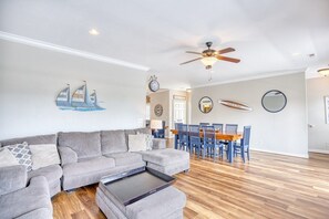 A modern living room with a sectional sofa, a dining table with chairs, and a ceiling fan. - Waterfront 5 BR w/ pool & elevator Sleeps 18 (North Myrtle Beach)