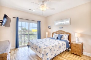 A bedroom with a bed, a ceiling fan, a TV, a window with curtains, and a nightstand with a lamp. - Waterfront 5 BR w/ pool & elevator Sleeps 18 (North Myrtle Beach)