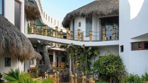 A resort with a wooden walkway, thatched-roof structures, and lush greenery. - Villa Crab | Puesta Del Sol Resort (La Peñita de Jaltemba,)