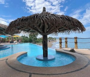 Relax in a hot tub surrounded by a thatched umbrella and enjoy the beach views.