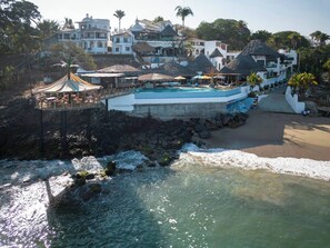 Relax by the infinity pool overlooking the ocean, with a shaded deck and access to the beach.