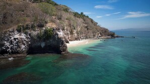 Un paisaje costero con aguas turquesas cristalinas, una playa arenosa y acantilados rocosos.
