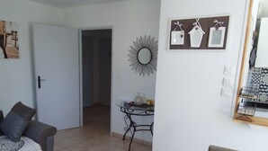 Een woonkamer met een bank, salontafel, eettafel en een keuken met een betegelde spatwand.