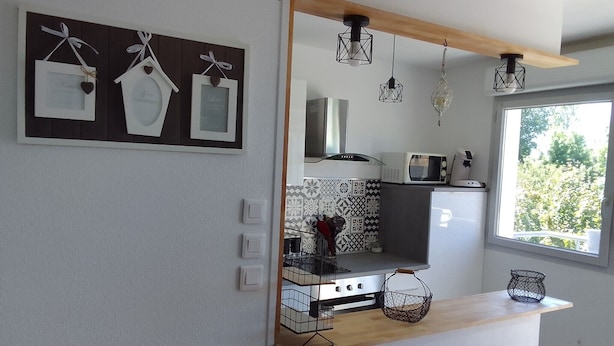 Een moderne keuken met een houten aanrecht, een ingebouwde kookplaat, een magnetron en hangende hanglampen.