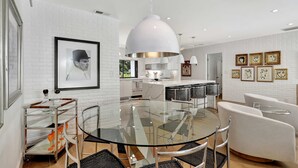 A modern kitchen with white brick walls, a glass dining table, and contemporary lighting fixtures.