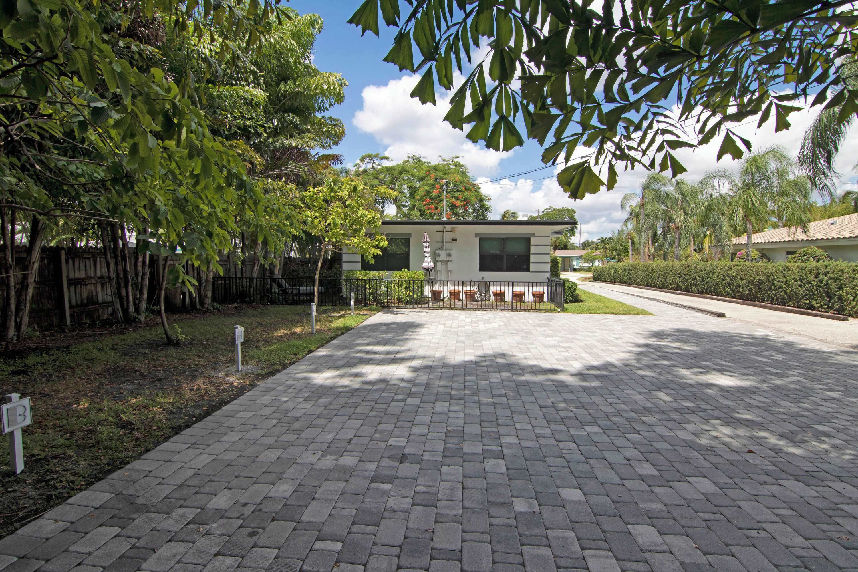 A paved driveway leading to a modern house with a small porch and a mailbox.