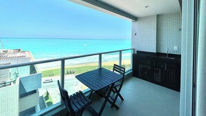 A balcony with a view of the ocean, a table, and chairs. - RN Studio Premium 613 - Frente Mar (Maceió)