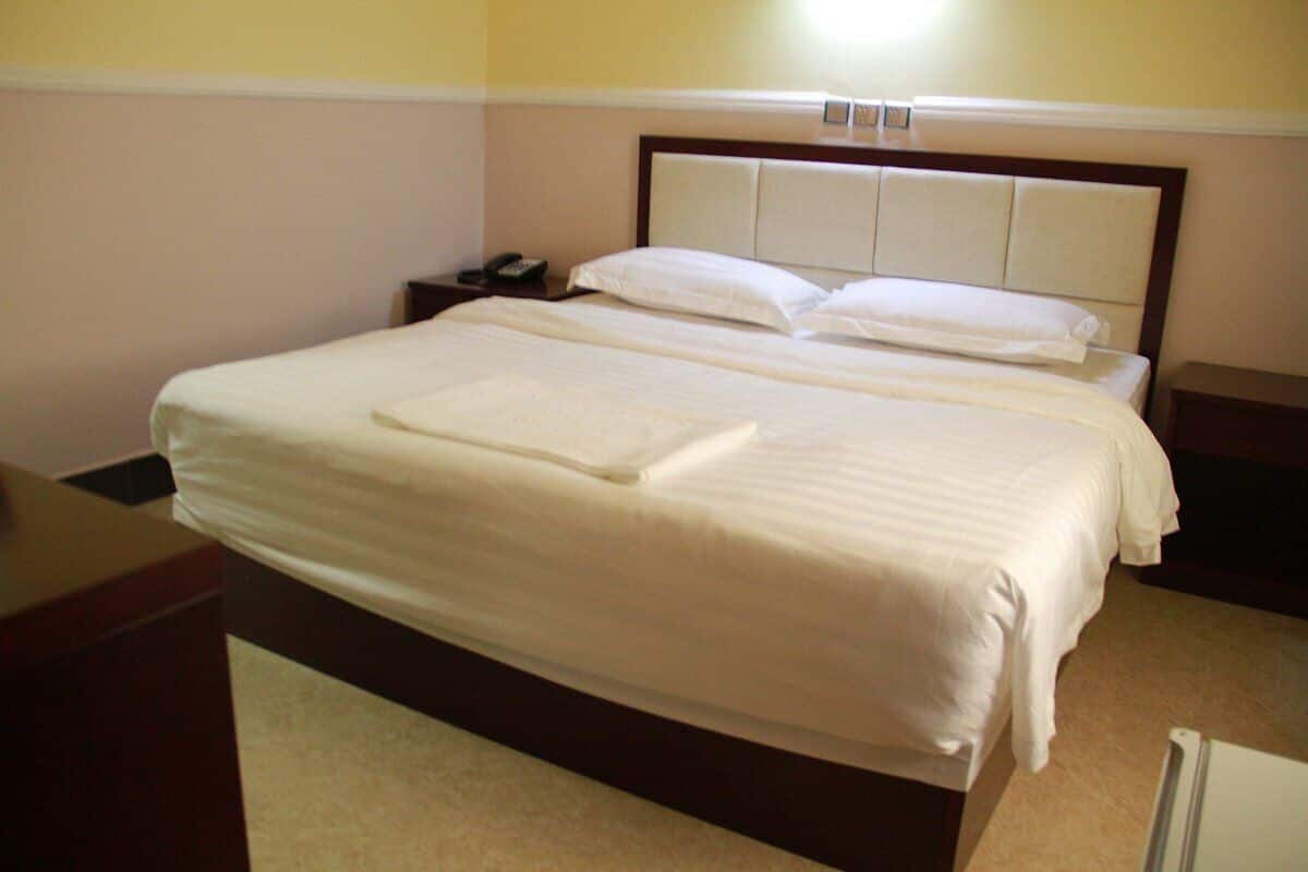 A hotel room with a large bed, a bedside table, and a nightstand.