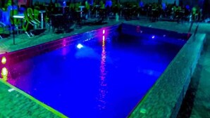 A swimming pool with a tiled edge and a roof overhead. - Greatwood Hotel (Owerri)
