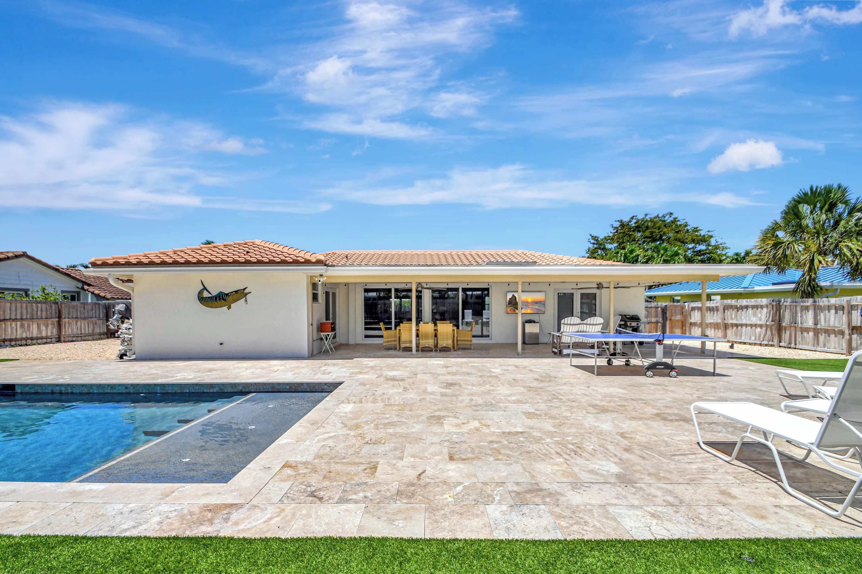 Un jardin avec une piscine, des meubles de patio et un espace salon abrité.