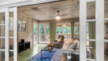 A spacious living area with a ceiling fan, a sofa, a coffee table, and a TV on a stand.
