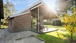 A modern house with a brick exterior, a glass door entrance, and a patio area with outdoor furniture.