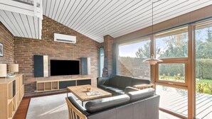 A modern living room with a brick wall, a flat-screen TV, a leather sofa, and a wooden coffee table.