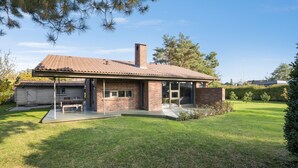 A single-story house with a brick exterior, a tiled roof, and a covered patio area.