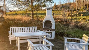 An outdoor seating area with a stone-built barbecue grill and white wooden benches. - Cozy home in Gravberget (Gravberget)