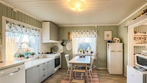 A compact kitchen with a dining area, featuring a stove, sink, refrigerator, and a small dining table with chairs. - Cozy home in Gravberget (Gravberget)