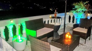 A balcony with wicker furniture, a table with a bottle and glasses, and candles.