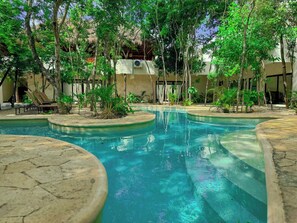 A swimming pool with surrounding trees and lounge chairs. - Estudio con Jacuzzi Privado NAIA B8 (Tulum)